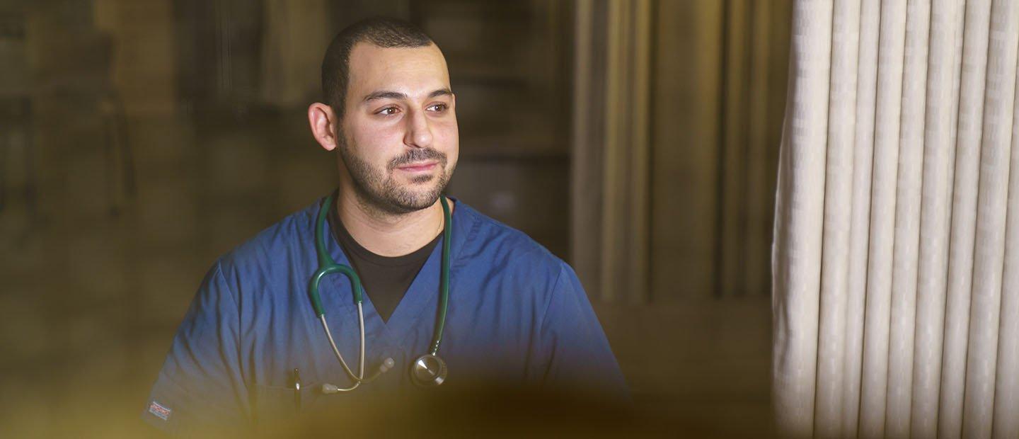 man wearing blue scrubs with a stethoscope around his neck